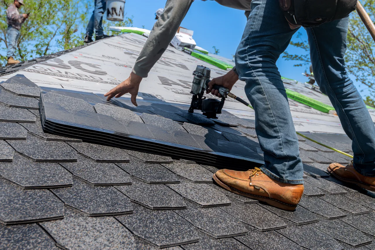 A roofer laying new shingles on a house